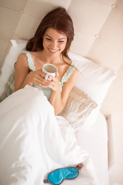 Lächelndes Mädchen im Bett trinkt Morgenkaffee — Stockfoto