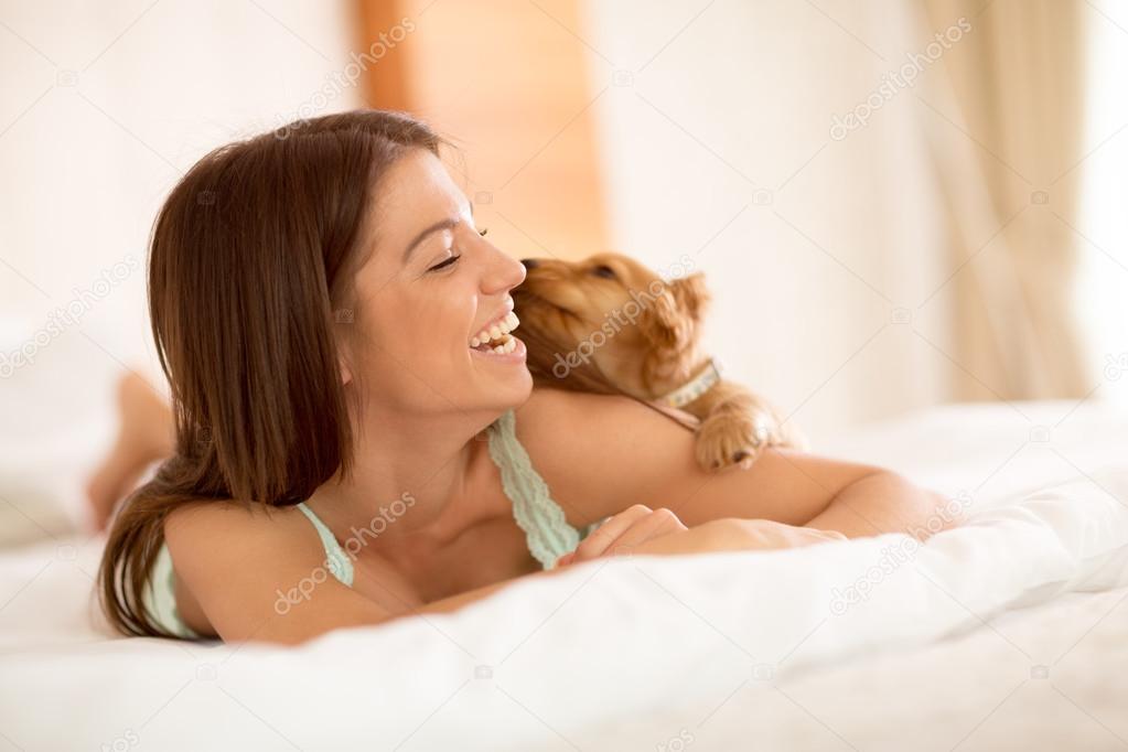 Cute puppy sniff girl in bed