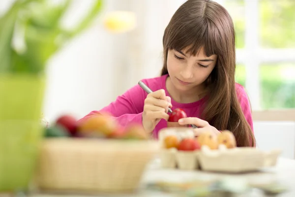 Concentrated little girl painting eggs — Stock Photo, Image