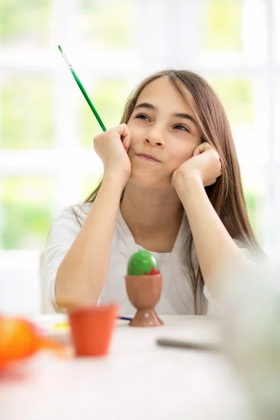 Lovely girl looking for ideas for painting Easter eggs — Stock Photo, Image