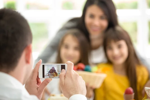 Far fotografera familjen genom smartphone hemma — Stockfoto