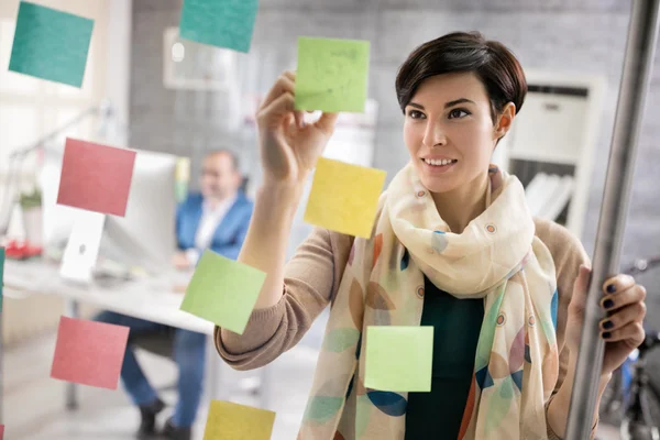 Working woman makes scheme on stickers at workplace — Stock Photo, Image