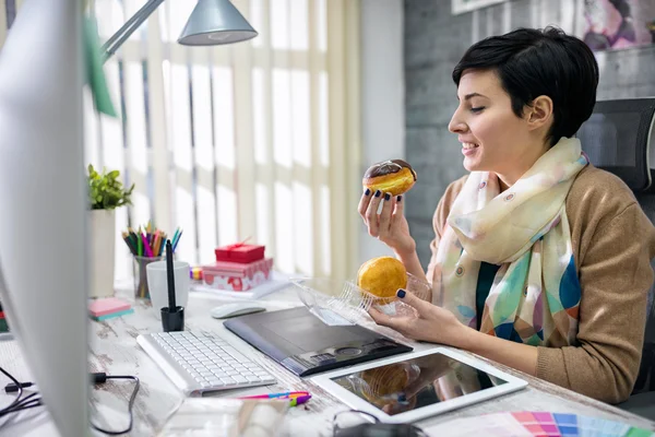 Задоволений дизайнер їсть пончик — стокове фото
