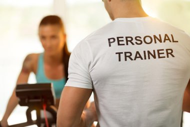 Spor salonunda Bisiklete binme makinede kadınla kişisel antrenör 