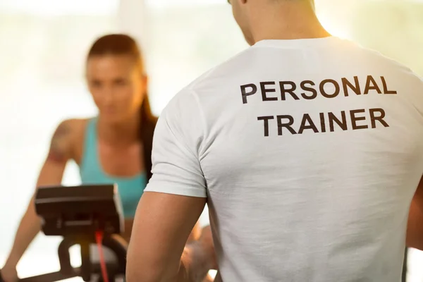 Persoonlijke trainer met vrouw op fietsen machine op de sportschool — Stockfoto