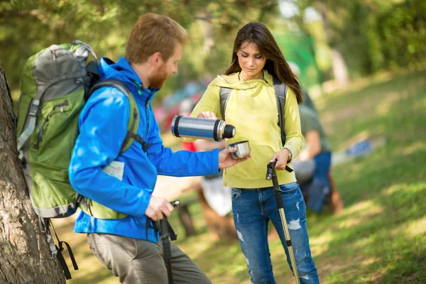 Caminhantes do sexo feminino derrama água de thermos para seu amigo masculino — Fotografia de Stock