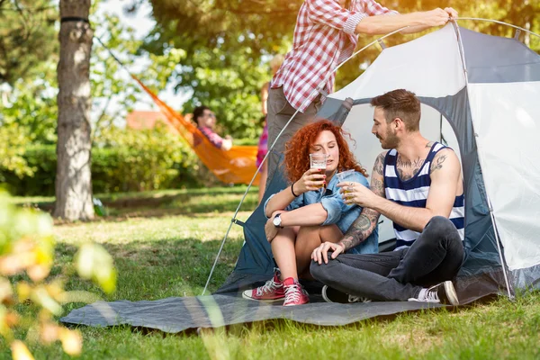 Masculino e feminino bebe cerveja na frente da tenda — Fotografia de Stock