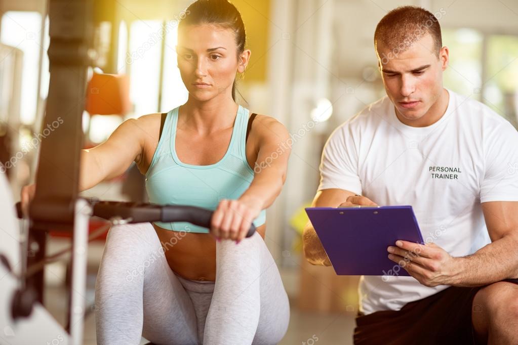 Trainer taking notes of attractive woman working out