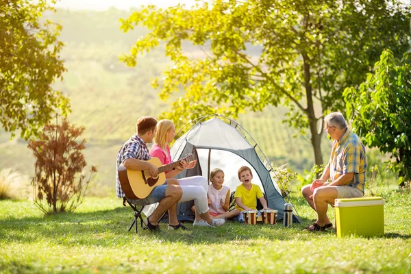 Genitori felici e bambini che si divertono in campeggio — Foto Stock
