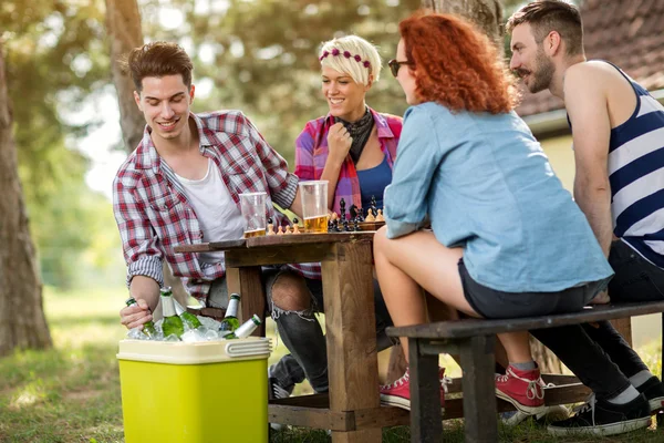 Cold beer refreshes youngsters while playing chess — Stock Photo, Image