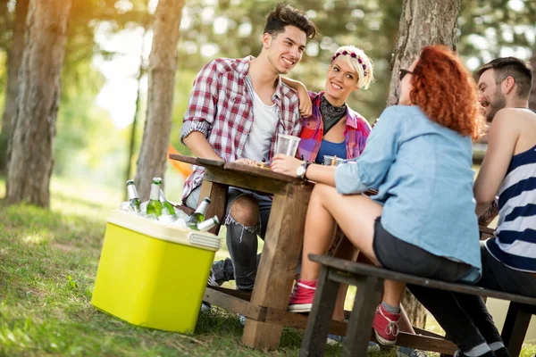 Meninas e caras se senta no banco na mesa de madeira, beber cerveja e mak — Fotografia de Stock