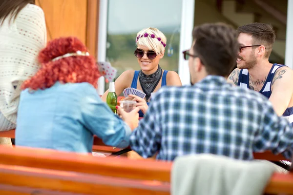 Guys and lassies in restaurant outdoor play cards and drink — Stock Photo, Image