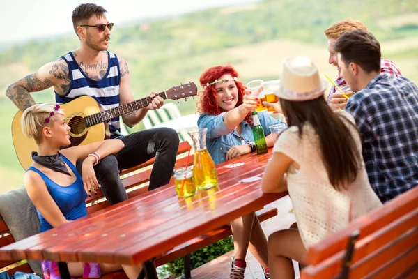 Meninas brinde com copos de cerveja enquanto menino tatuado tocar guitarra — Fotografia de Stock