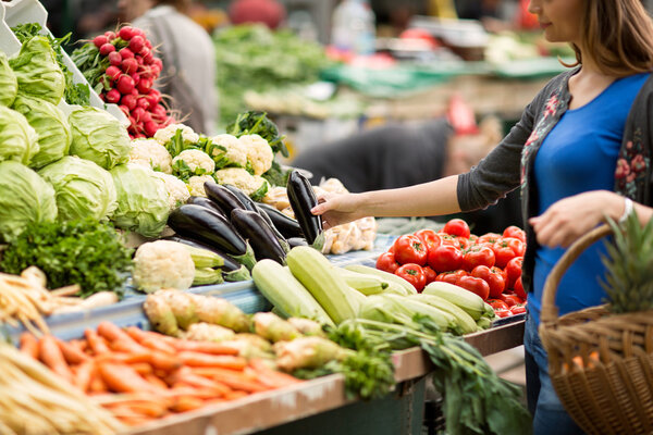 Young woman buying vegetable on stall