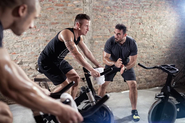 Trainer gives support man on a spinning training — Stock Photo, Image