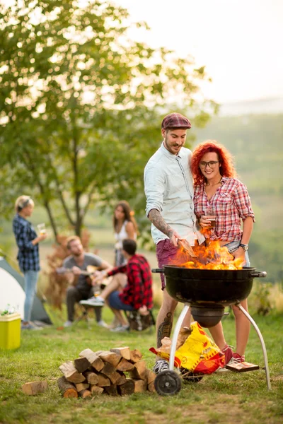 Guy put log on grill fire and hug curly girl — Stock Photo, Image