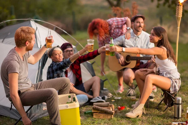 Young group toasting with bottles and glasses of beer in campgro — Stockfoto