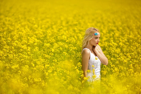 Young woman walking through a field of flowers — Stock Photo, Image