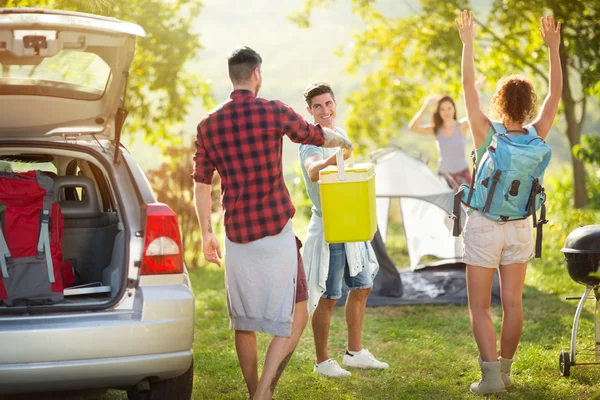 Amigos felizes desempacotando carro para camping viagem — Fotografia de Stock