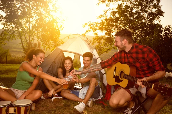 Jovens sentados ao lado da tenda e brindar com cerveja — Fotografia de Stock