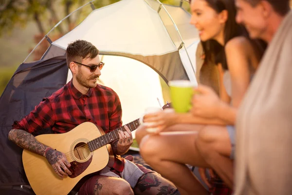 Campista homem na companhia de seus amigos toca guitarra — Fotografia de Stock