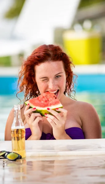 Ginger curly girl på piscine uppfriskande med vattenmelon — Stockfoto