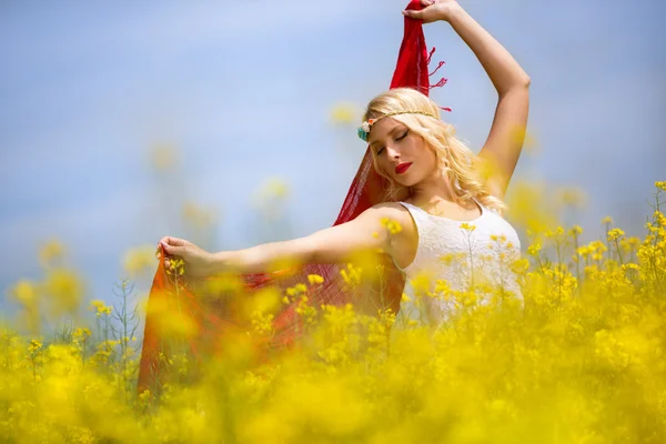 Beautiful young girl with red scarf in field — Stock Photo, Image
