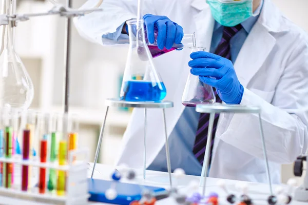 Mano de científico sosteniendo una cristalería de laboratorio para un experimento — Foto de Stock