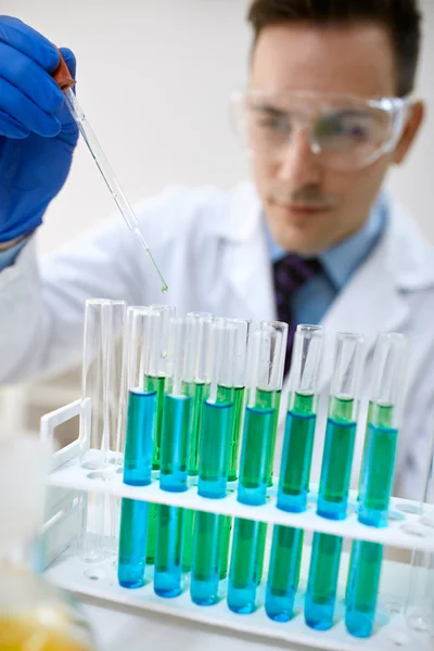 Pipeta de laboratorio con gota de líquido verde sobre tubo de ensayo — Foto de Stock