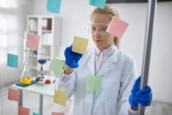 Científica en laboratorio escribe fórmulas químicas —  Fotos de Stock