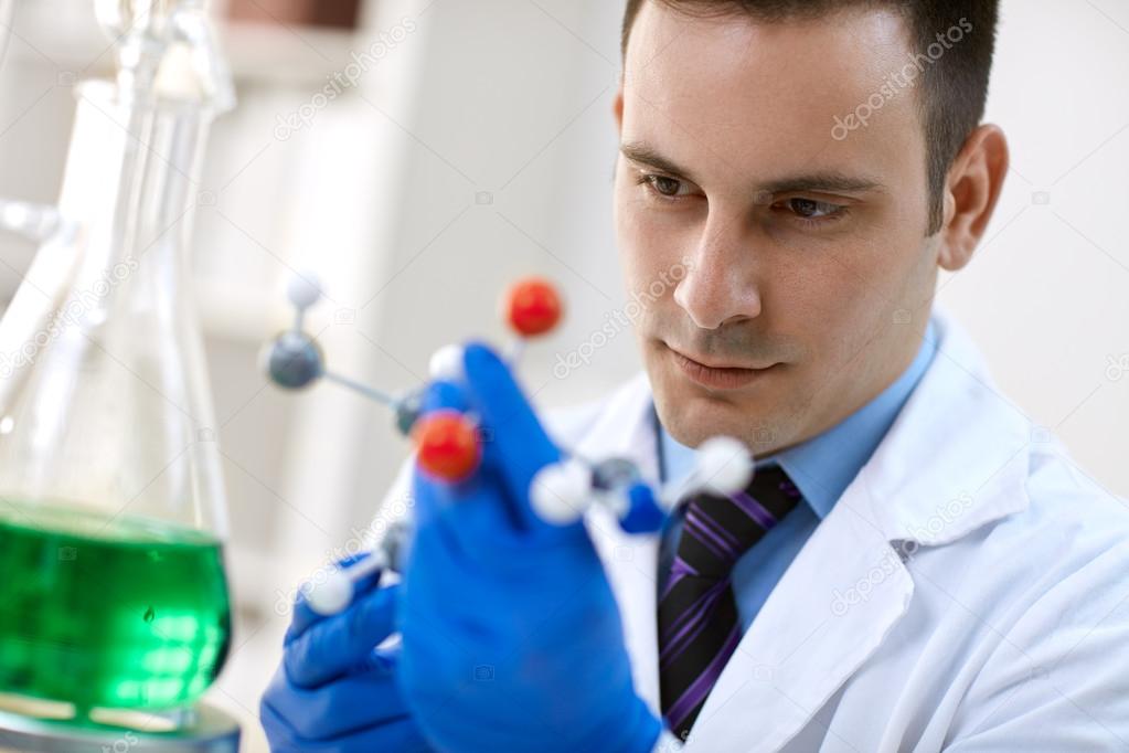 young male doctor examining molecular structure in laborator