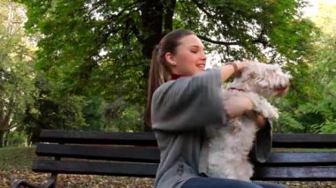 Genç kadın parkta açık beyaz köpeği sarılma 