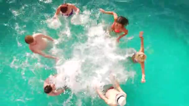 Voo aéreo: Grupo feliz de amigos desfrutando de festa na piscina de verão salpicando na água — Vídeo de Stock