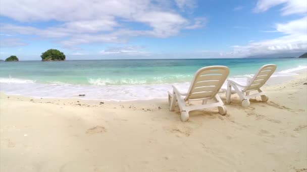 Εναέρια ΠΤΗΣΗΣ: δύο κενή καρέκλα σε μια παραλία από τον ωκεανό — Αρχείο Βίντεο