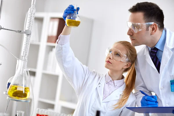 Студент-химик держит фляжку в лаборатории — стоковое фото