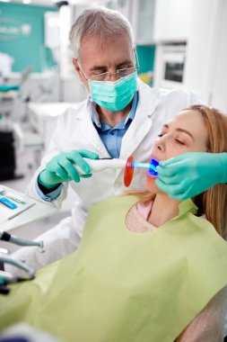 Erkek diş hekimi ve diş dolguları ışık ile kuru sabit