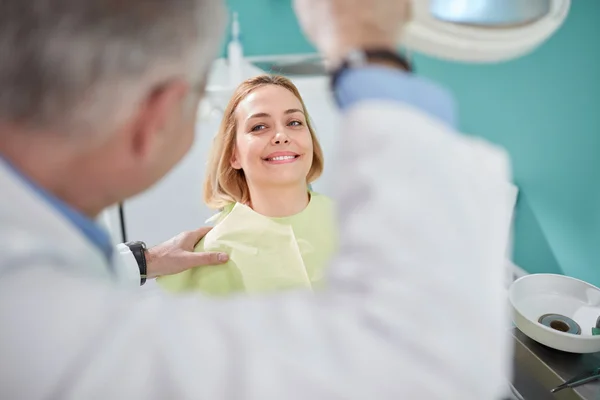 Bella paziente femminile sorridente in sedia dentale — Foto Stock