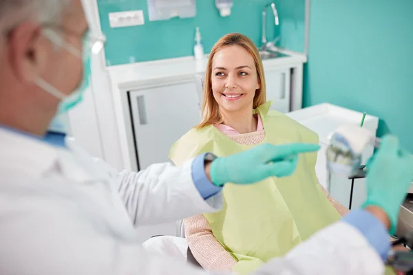 Patiente écouter son dentiste tout en expliquant le problème sur le modèle de mâchoire — Photo