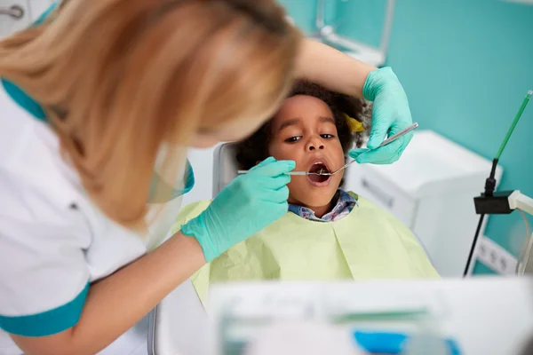 Tandartsassistente look met tandheelkundige spiegel girl's tanden — Stockfoto