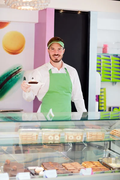 Worker in pastry shop holding cupcake — Stock Photo, Image
