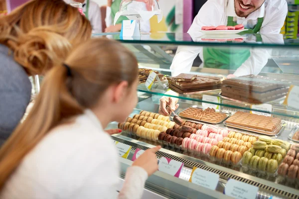 In pastry shop girl choose macarons from showcase — Stock Photo, Image