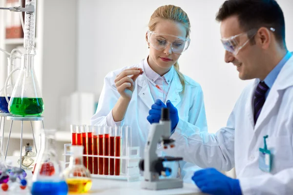 Dos jóvenes científicos haciendo un experimento en un laboratorio — Foto de Stock