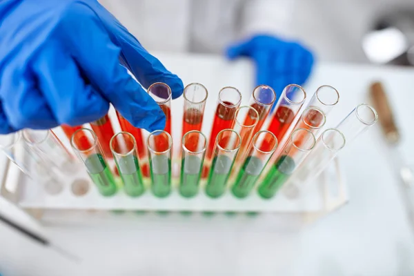 Mano del científico sosteniendo un tubo de ensayo de vidrio de laboratorio — Foto de Stock