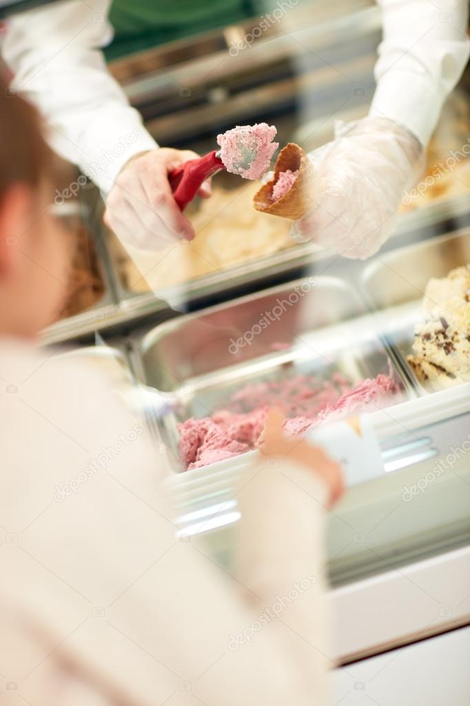 Vendor's hands putting ice cream in cone  