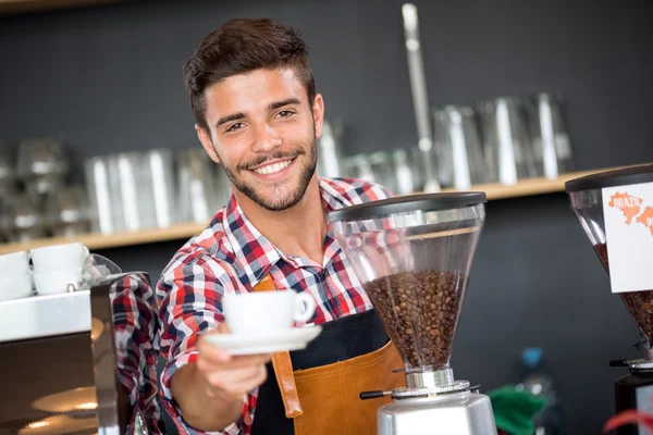 Улыбающийся официант предлагает чашку кофе — стоковое фото