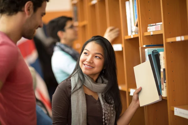 Asiatisk student att välja böcker i biblioteket — Stockfoto