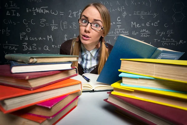 Kitaplarla dolu bir masada oturan öğrenci — Stok fotoğraf