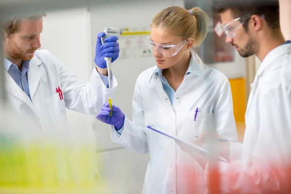 Teamarbeit im Chemielabor legte Probe von Flüssigkeit in Testpipette — Stockfoto