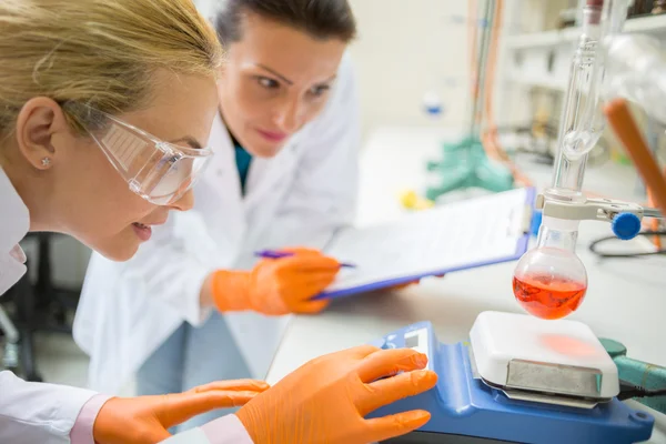 Assistantes féminines ajustent le dispositif pour mesurer le liquide — Photo