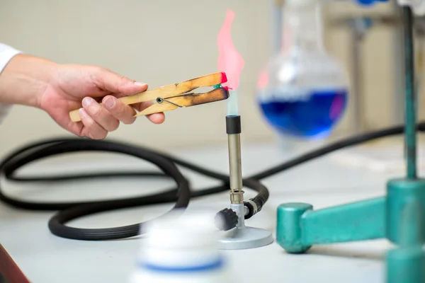 Primo piano della mano con ago bruciante nelle pinze da laboratorio — Foto Stock